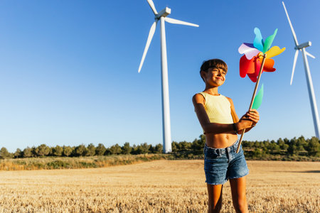 Girl playing in the meadow at sunset with colorful pinwheel in her hands.の写真素材