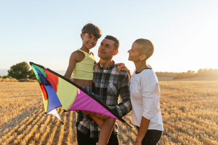 Mom, dad and daughter together holding a colorful kite on a sunny day.の写真素材