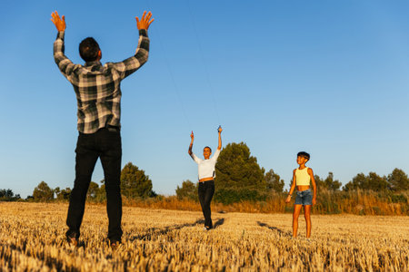Harmonious family flying a kite in a summer field.の写真素材
