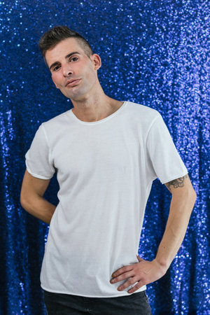 Vertical portrait of a gay man standing in blue backgroundの写真素材
