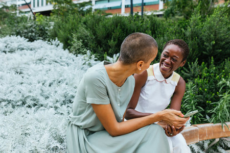 Joyful Moment Between Two Businesswomen Sharing Laughter in a Lush Urban Gardenの写真素材