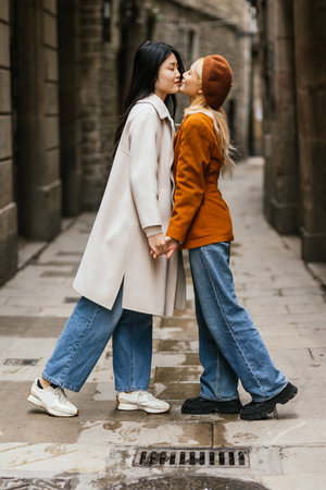 Asian lesbian couple holding hands and kissing on the streets of Barcelona, Spain.の写真素材