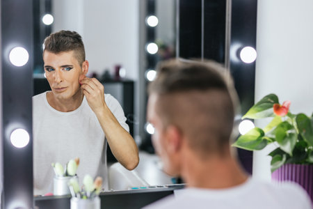 Gay man using mascara to make up in backstageの写真素材