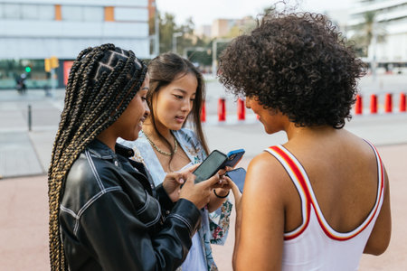 Women and transgender friend using phone in the streetの写真素材