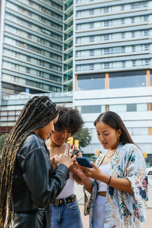 Vertical photo of diverse friends using phone outdoorsの写真素材