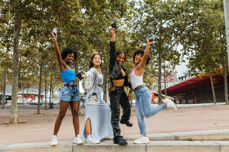 Women and transgender person jumping celebrating together outdoorsの写真素材