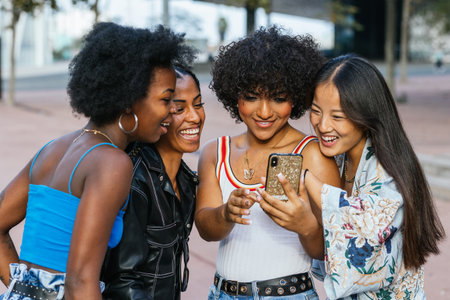Multi-ethnic friends standing together using phone in the streetの写真素材