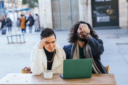 Stressed men looking frustrated while using laptop outdoors at cafe.の写真素材