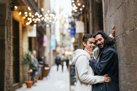 Male couple embracing while standing near wall outdoors.の写真素材