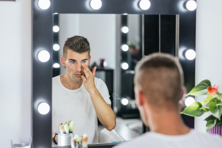 Drag queen artist applying concealer while doing his makeup in the dressing room.の写真素材