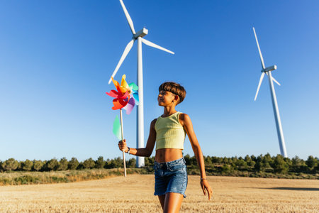 Smiling girl playing with a colorful pinwheel in the sunlight.の写真素材