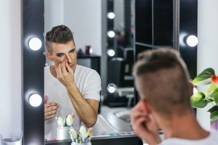 Drag queen artist applying makeup with sponge while getting ready in a dressing room.の写真素材