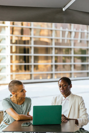 Two businesswomen working on a laptop at a tableの写真素材