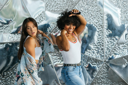 Transgender woman posing with her latina friend in front of a shiny sculpture.の写真素材