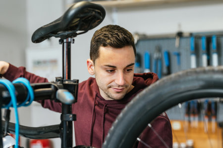 Portrait of the bike mechanic looking towards the wheel with his hand resting on the handlebar.の写真素材