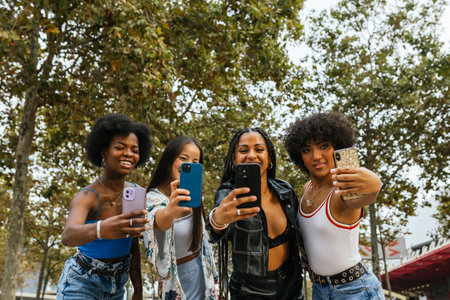 Four female friends enjoying an outdoor selfie session on a sunny dayの写真素材