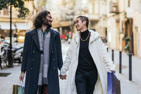 Happy gay couple holding hands while carrying shopping bagsの写真素材