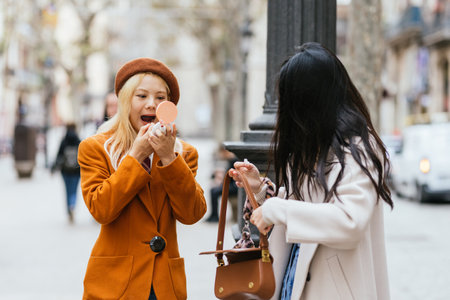 Two young women applying make up on the streetの写真素材