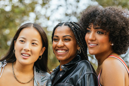Vibrant young women of different ethnicities posing closely together outdoors.の写真素材