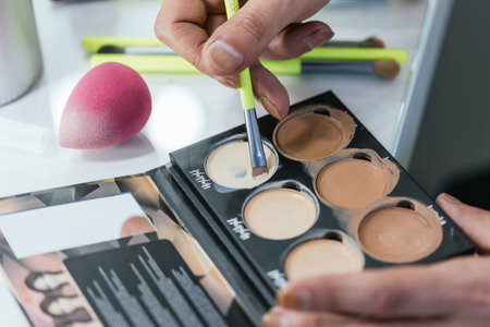Close-up of a drag queens hands applying foundation from a paletteの写真素材