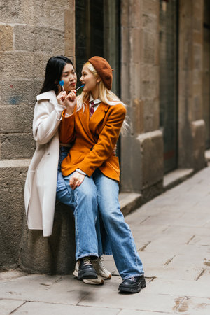 Two young tourists eating lollipops and relaxing in barcelonaの写真素材