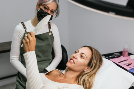 Satisfied client checking microblading results in mirror at beauty salon