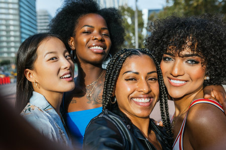 Diverse group of joyful female friends taking a selfie on a sunny urban afternoonの写真素材
