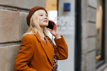 Young woman wearing beret is talking on smartphone in the streetの写真素材