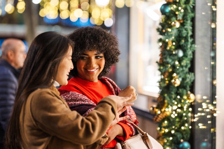 Two young women window shopping pointing christmas lights decorationsの写真素材
