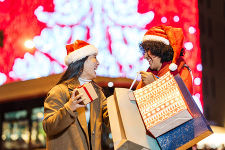 Two happy friends exchanging christmas gifts on illuminated streetの写真素材