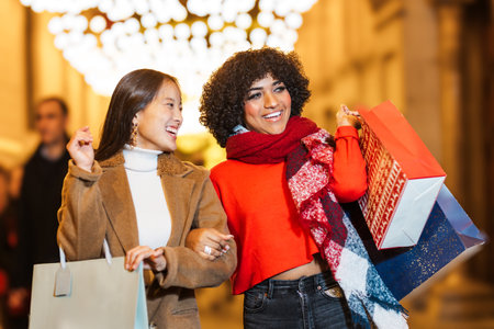 Two women holding shopping bags are enjoying christmas shoppingの写真素材