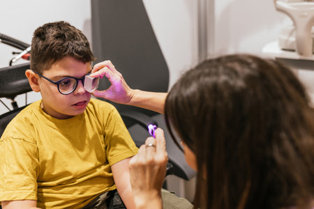 Optometrist examining eyesight of child with cerebral palsy in clinicの写真素材