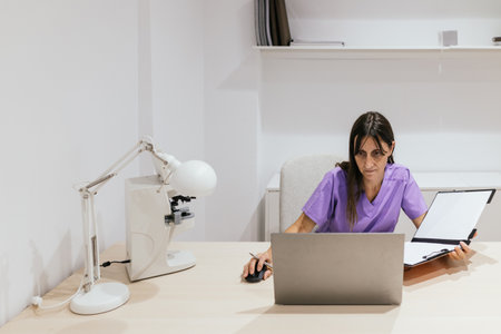 Female optometrist working at her desk in her officeの写真素材