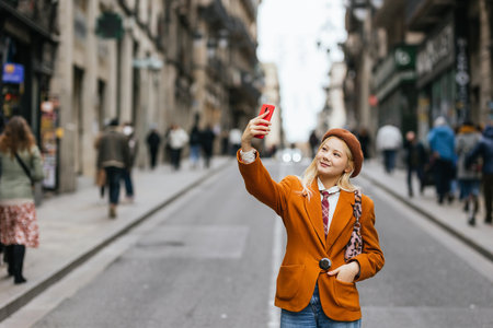 Young woman taking selfie walking down the street in barcelonaの写真素材