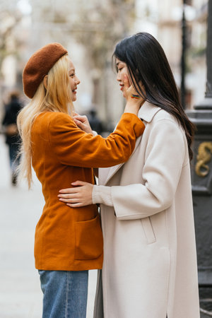 Two women in coats hugging and smiling at each otherの写真素材