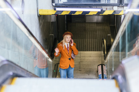 Young businesswoman talking on phone while leaving subway stationの写真素材