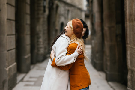 Two young women are hugging while walking in a barcelona alleyの写真素材
