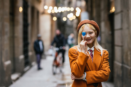 Young woman holding heart shape lollipop in barcelona streetの写真素材