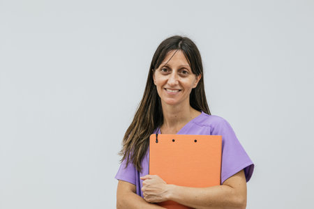 Female optometrist smiling and holding a clipboard on a white backgroundの写真素材