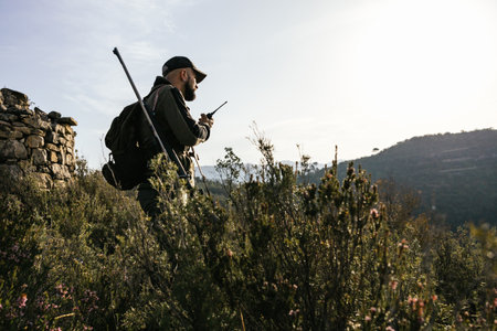 Hunter using walkie talkie on mountain top during huntの写真素材