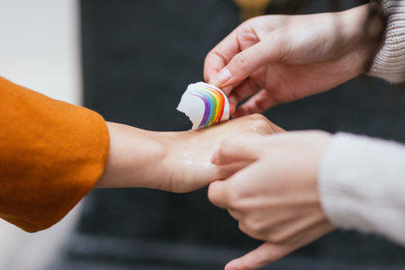 Woman applying a temporary tattoo of a lgbt rainbow flag on a woman hand.の写真素材