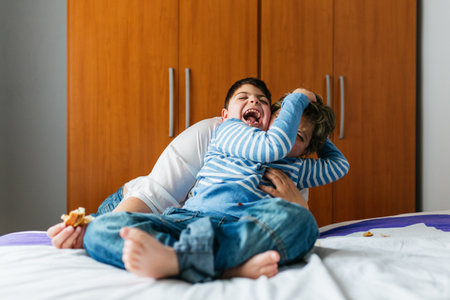 Mother and son with disability playing together on bedの写真素材