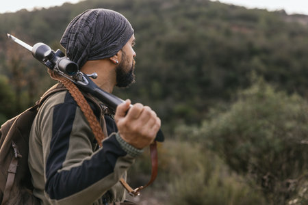 Hunter walking through forest carrying rifle on shoulderの写真素材