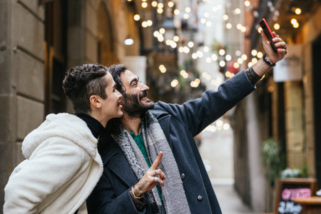 Gay couple taking selfie in city with christmas lightsの写真素材