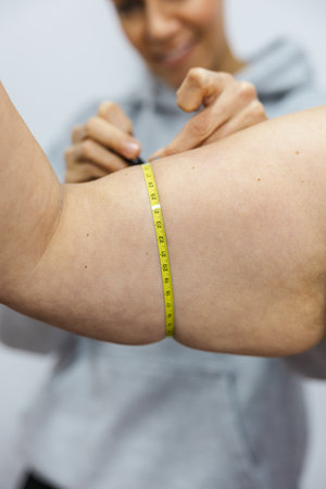 Nutritionist measuring womans arm with tape measure for weight loss progressの写真素材