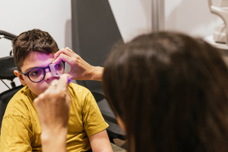 Optometrist examining eyesight of child with cerebral palsy in clinicの写真素材