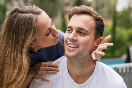 Playful couple applying sunscreen or exfoliating scrub outdoorsの写真素材