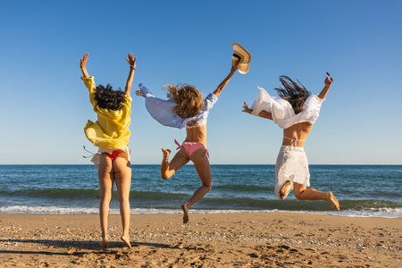 Friends jumping on the beach enjoying summer holidaysの写真素材