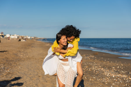Two happy women piggybacking on the beach, enjoying summer vacationの写真素材