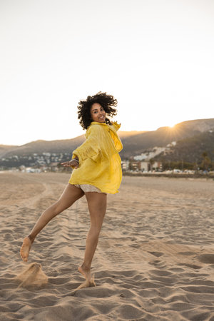 Carefree latin woman dancing on the beach at sunsetの写真素材